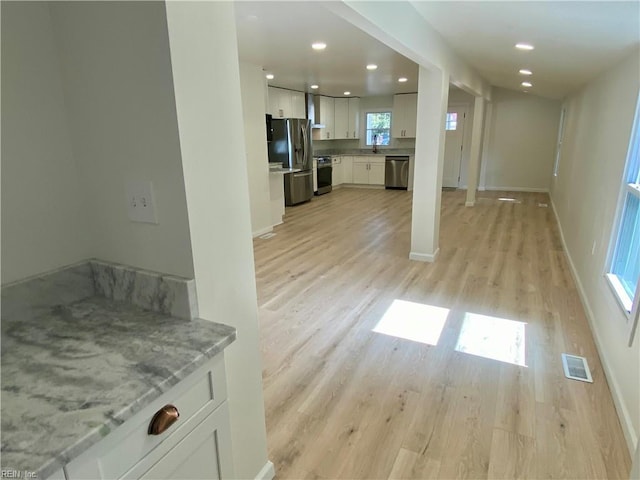 unfurnished living room with light wood-style flooring, visible vents, a sink, and recessed lighting