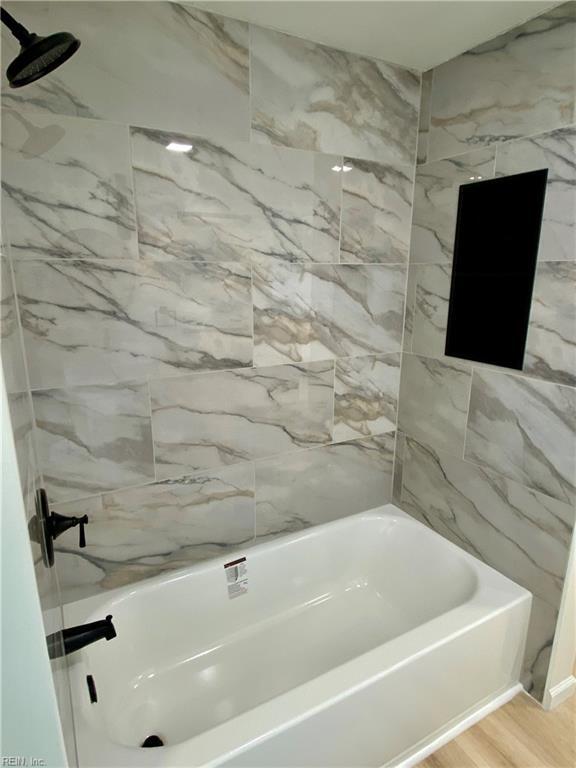 bathroom with shower / washtub combination and wood finished floors