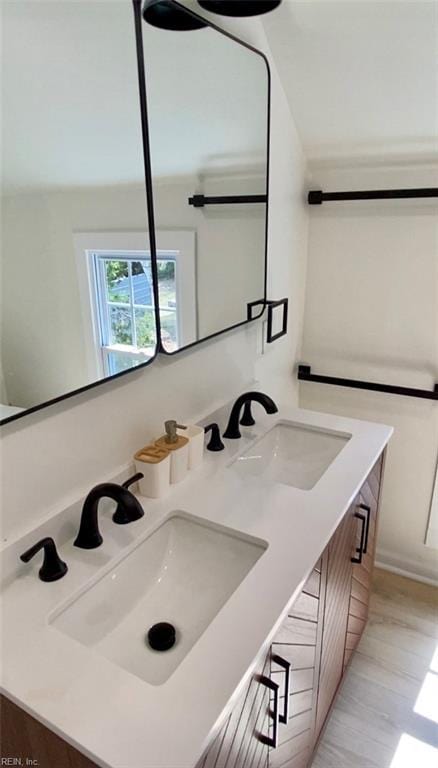 bathroom featuring double vanity, lofted ceiling, a sink, and wood finished floors