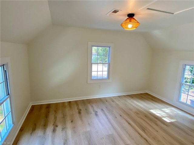 bonus room with vaulted ceiling, light wood finished floors, visible vents, and a healthy amount of sunlight