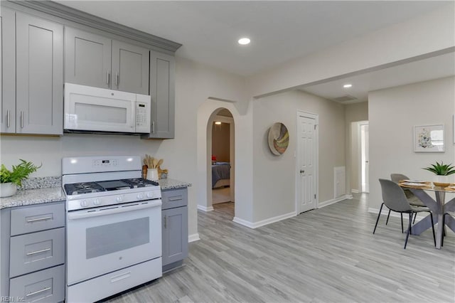 kitchen with arched walkways, white appliances, light wood finished floors, and gray cabinetry