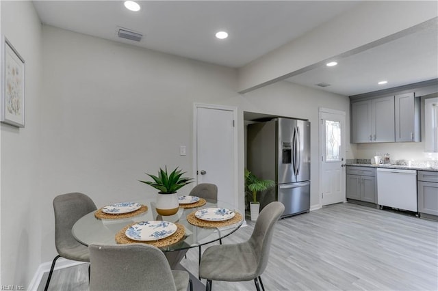 dining room with baseboards, light wood finished floors, visible vents, and recessed lighting