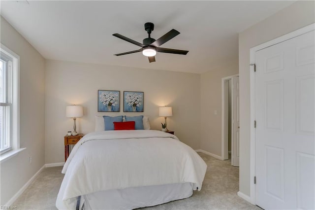 bedroom featuring light carpet, multiple windows, and baseboards