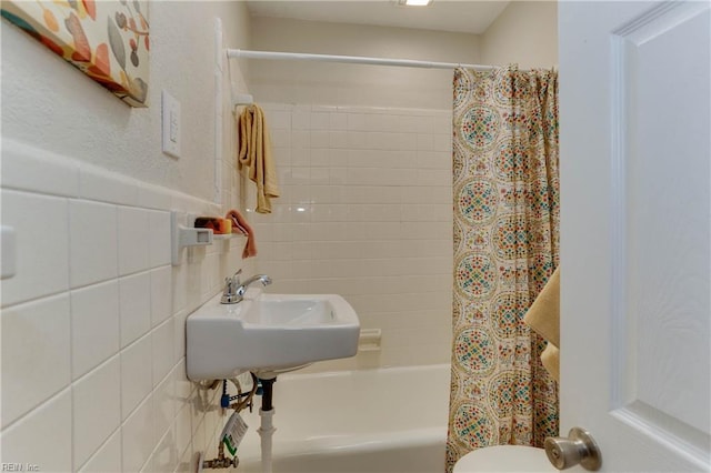 full bathroom with a sink, shower / tub combo with curtain, tile walls, and toilet