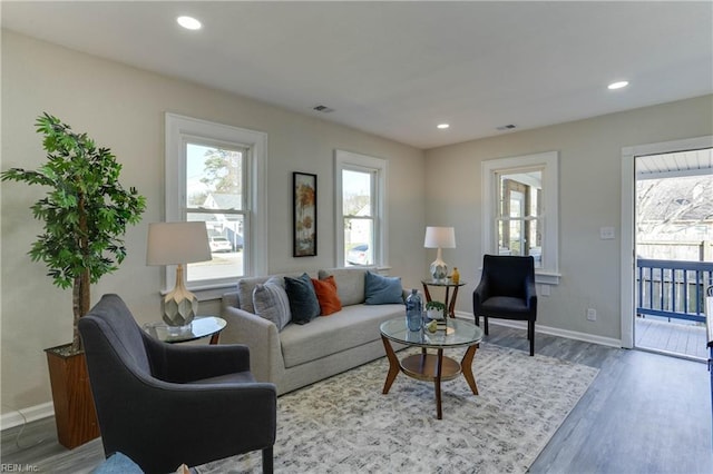 living room featuring baseboards, visible vents, wood finished floors, and recessed lighting