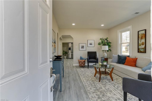 living area featuring arched walkways, recessed lighting, wood finished floors, visible vents, and baseboards