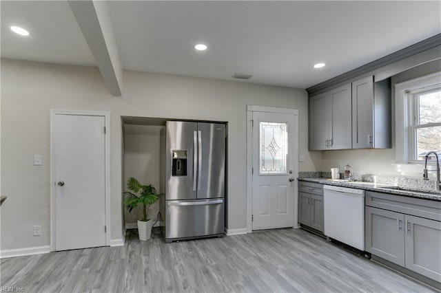 kitchen with stainless steel fridge, white dishwasher, gray cabinetry, light wood-type flooring, and a sink