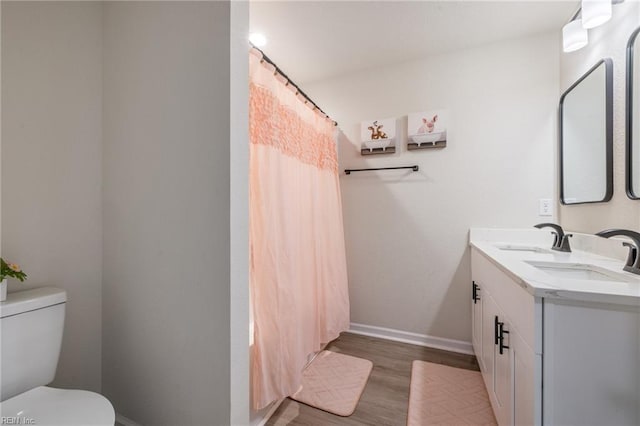 bathroom with wood finished floors, a sink, toilet, and baseboards