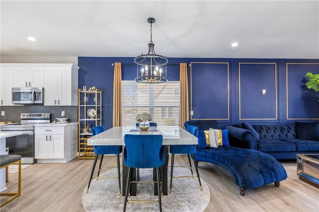 dining space featuring recessed lighting, light wood-type flooring, and a notable chandelier