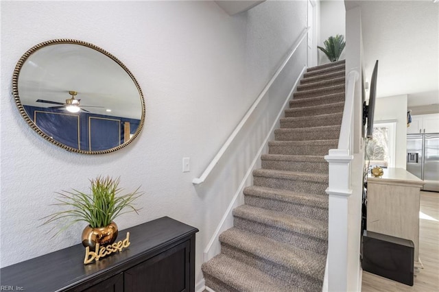 stairway featuring wood finished floors and a ceiling fan