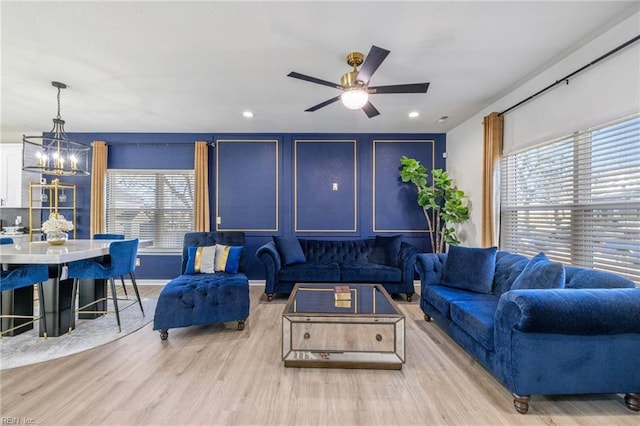 living room with recessed lighting, wood finished floors, and ceiling fan with notable chandelier