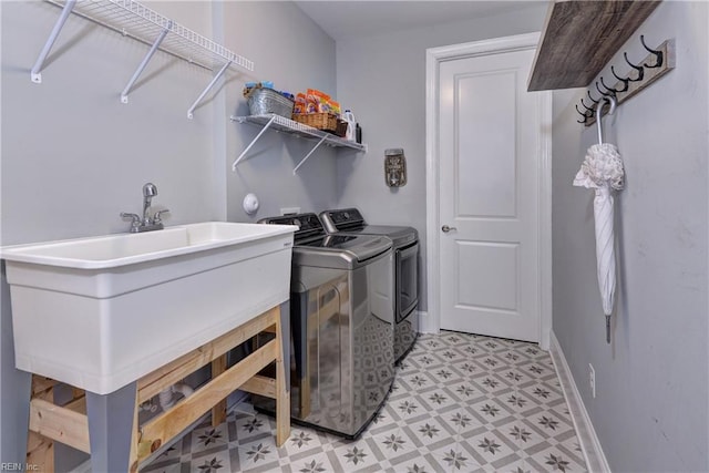 clothes washing area featuring laundry area, baseboards, washer and clothes dryer, and light floors