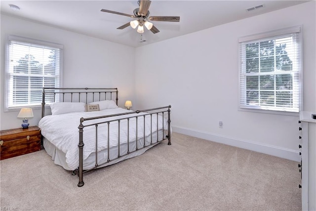 bedroom with a ceiling fan, visible vents, light carpet, and baseboards