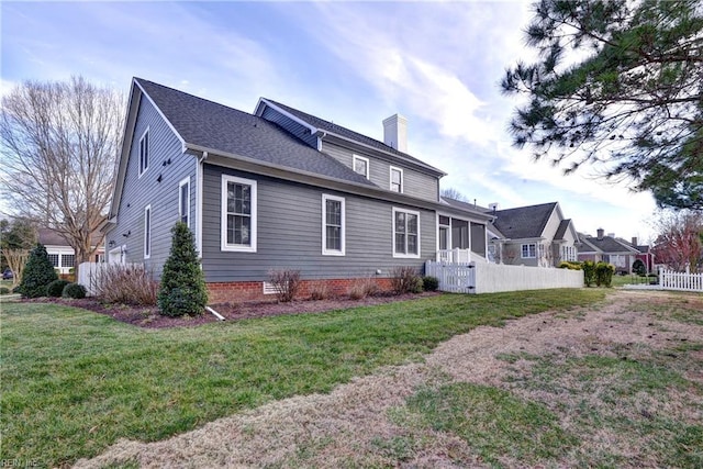 view of front facade featuring a sunroom, a chimney, roof with shingles, fence, and a front lawn