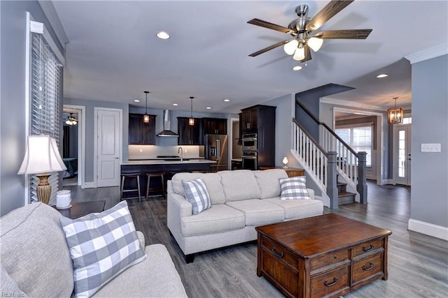 living room featuring recessed lighting, ceiling fan with notable chandelier, wood finished floors, baseboards, and stairway