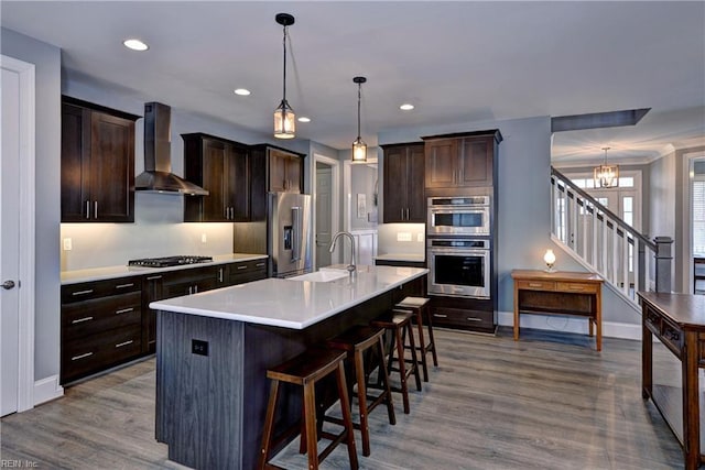 kitchen with wall chimney exhaust hood, stainless steel appliances, a sink, and light countertops