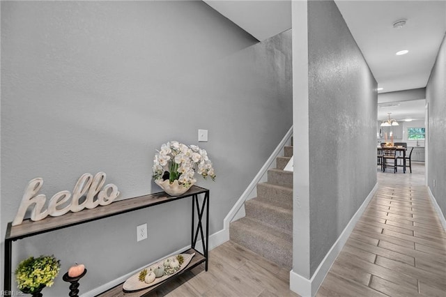 staircase featuring a textured wall, wood finished floors, and baseboards