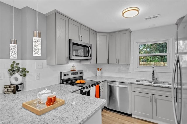 kitchen featuring a sink, appliances with stainless steel finishes, gray cabinets, and visible vents