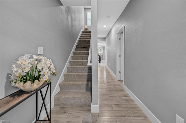 stairway featuring wood tiled floor, a textured wall, baseboards, and recessed lighting