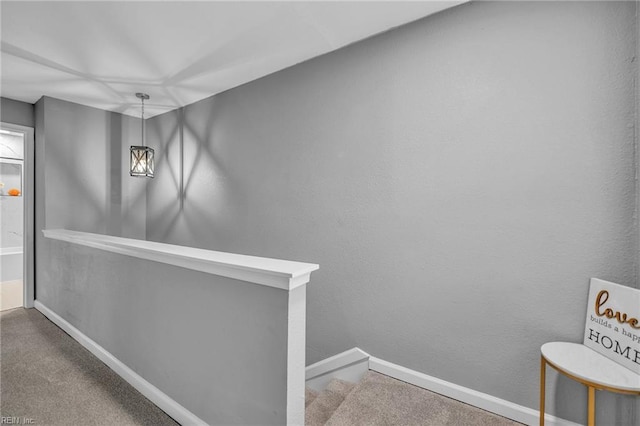 corridor with carpet, baseboards, and an upstairs landing