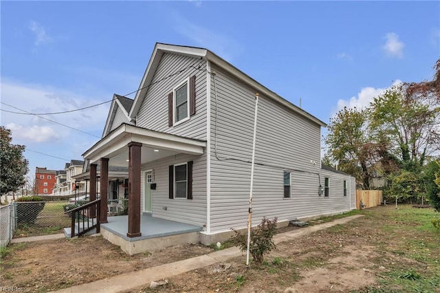 view of home's exterior with covered porch and fence