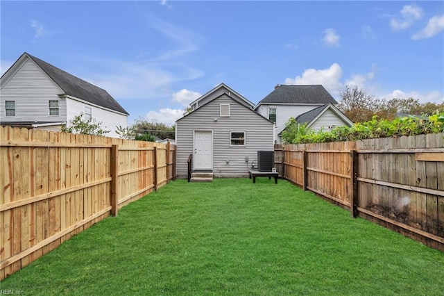 rear view of house featuring entry steps, central AC, a yard, and a fenced backyard