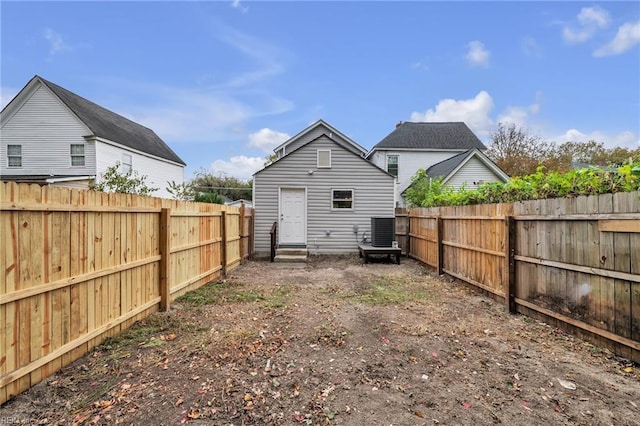 rear view of house with entry steps, central air condition unit, and a fenced backyard