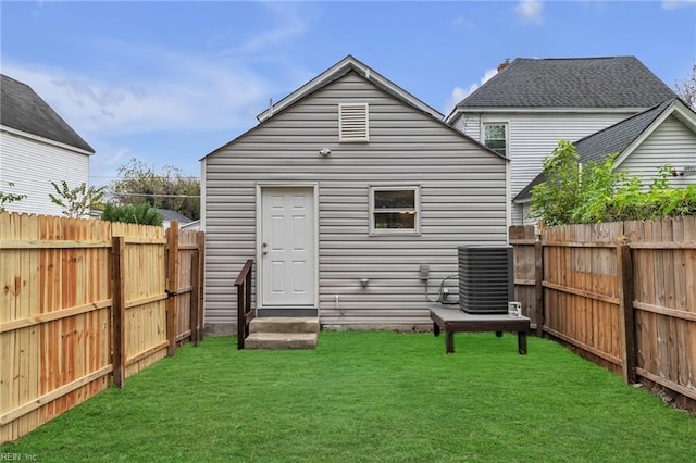 back of house featuring entry steps, central AC, a yard, and a fenced backyard