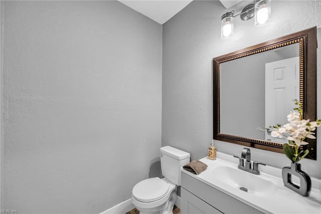 bathroom with baseboards, a textured wall, vanity, and toilet