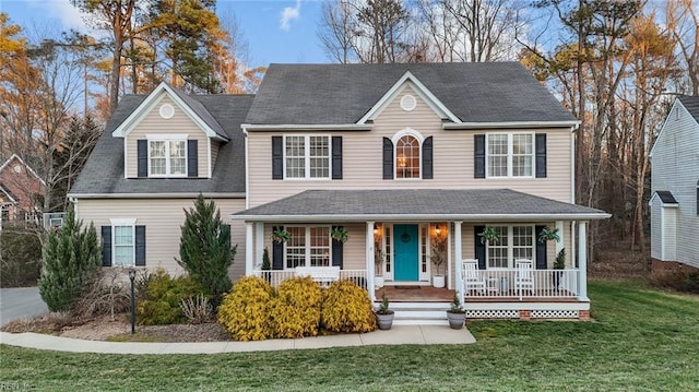 view of front of house with a front yard, covered porch, and roof with shingles