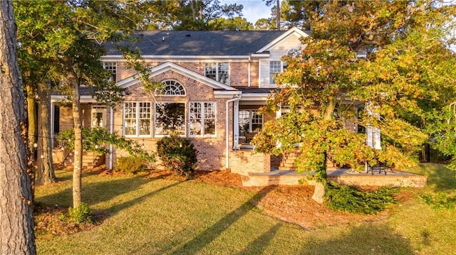 view of front of home featuring a patio, brick siding, and a front lawn