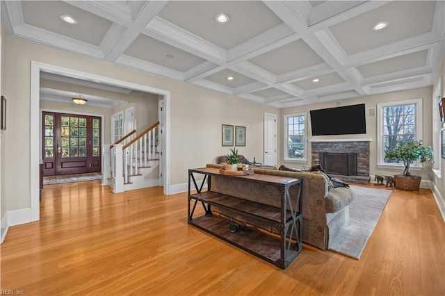 living area with light wood finished floors, beam ceiling, coffered ceiling, and stairs