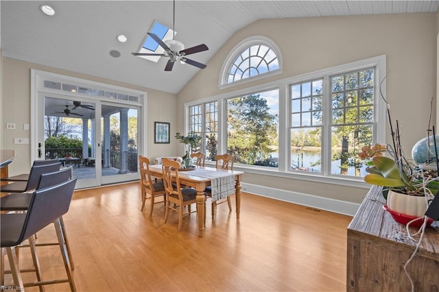 dining space featuring light wood-style flooring, a skylight, baseboards, and ceiling fan