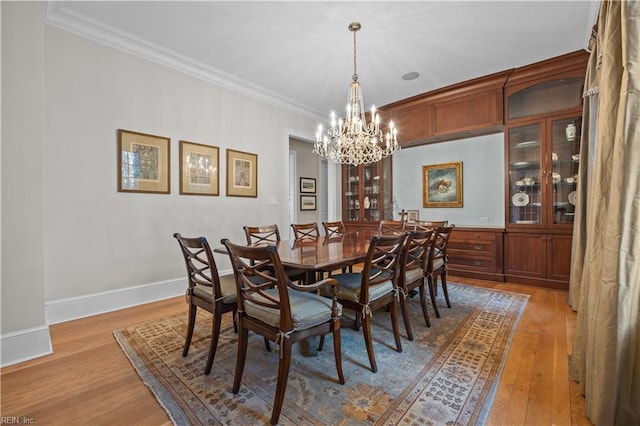 dining room with an inviting chandelier, light wood-style floors, baseboards, and ornamental molding