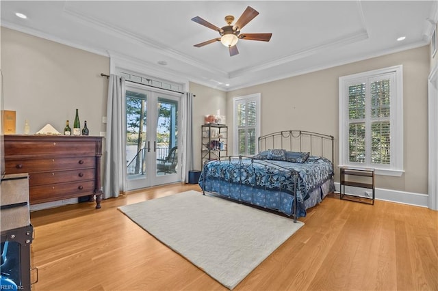 bedroom with french doors, a raised ceiling, multiple windows, and access to exterior