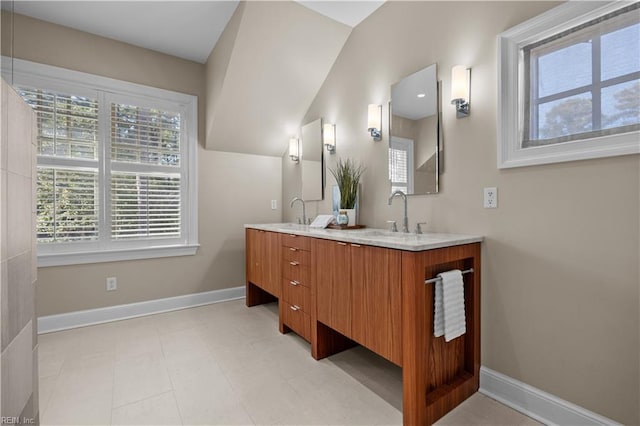 bathroom with double vanity, baseboards, lofted ceiling, and a sink