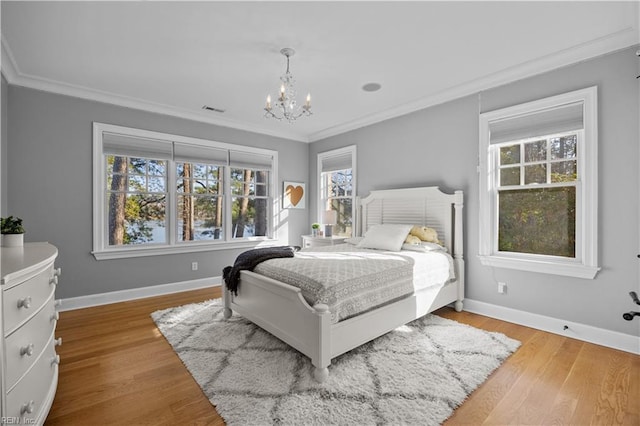 bedroom with crown molding, wood finished floors, visible vents, and baseboards