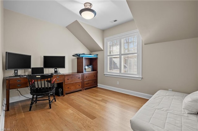 office area featuring visible vents, lofted ceiling, baseboards, and wood finished floors