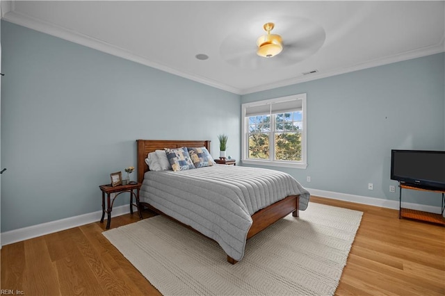 bedroom featuring crown molding, wood finished floors, visible vents, and baseboards