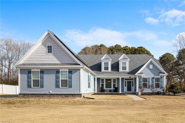 view of front of house featuring a shingled roof, fence, and a front lawn