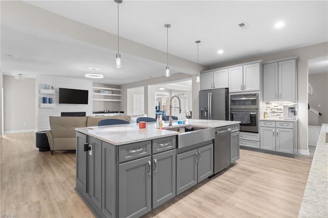 kitchen featuring stainless steel appliances, light wood-style floors, a sink, and gray cabinetry