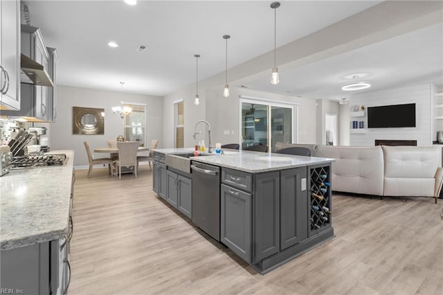 kitchen with light wood finished floors, appliances with stainless steel finishes, gray cabinetry, under cabinet range hood, and a sink