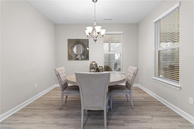 dining room featuring light wood-style flooring, baseboards, and a chandelier