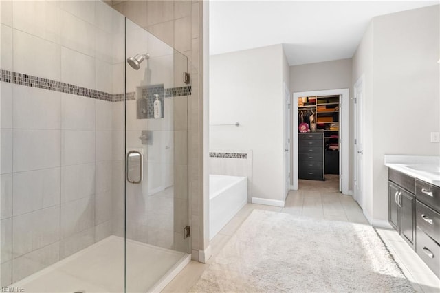 full bathroom featuring a stall shower, tile patterned floors, a walk in closet, vanity, and a bath