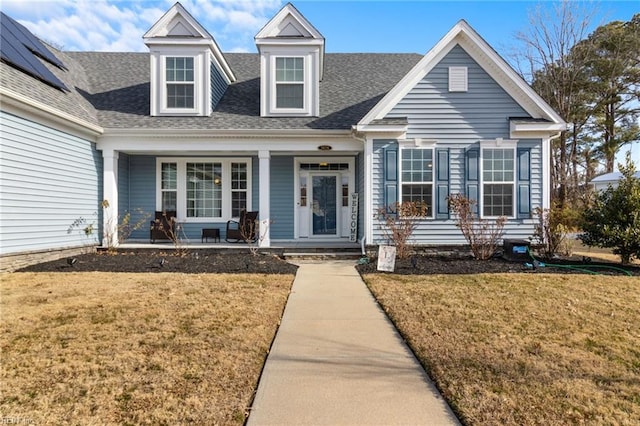 cape cod-style house featuring a shingled roof, a porch, and a front yard