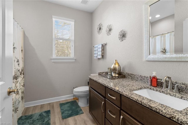 bathroom featuring toilet, wood finished floors, vanity, and baseboards