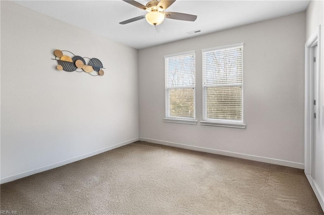 carpeted spare room featuring a ceiling fan, visible vents, and baseboards