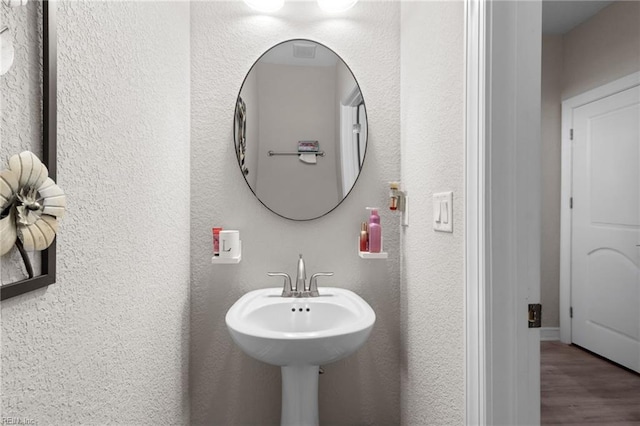 bathroom featuring wood finished floors and a textured wall