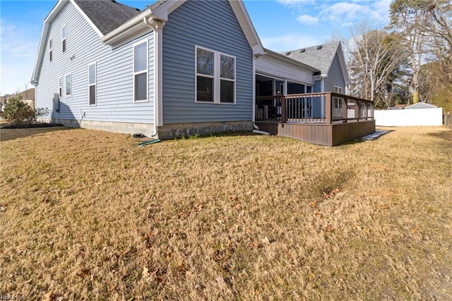 back of property featuring a wooden deck, a shingled roof, and a yard