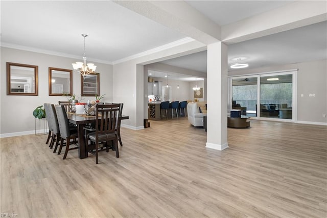 dining space with a chandelier, crown molding, light wood-style floors, and baseboards